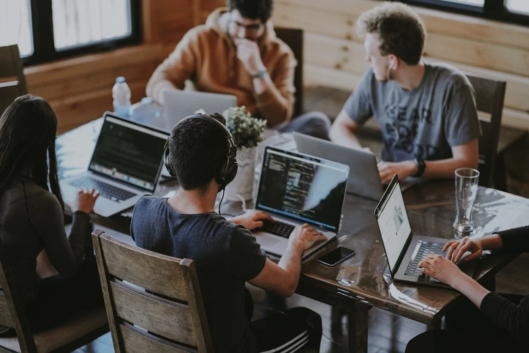 A team working together on laptops around a wooden table