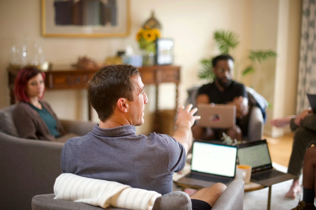 A small group meeting in a living room, one person speaking